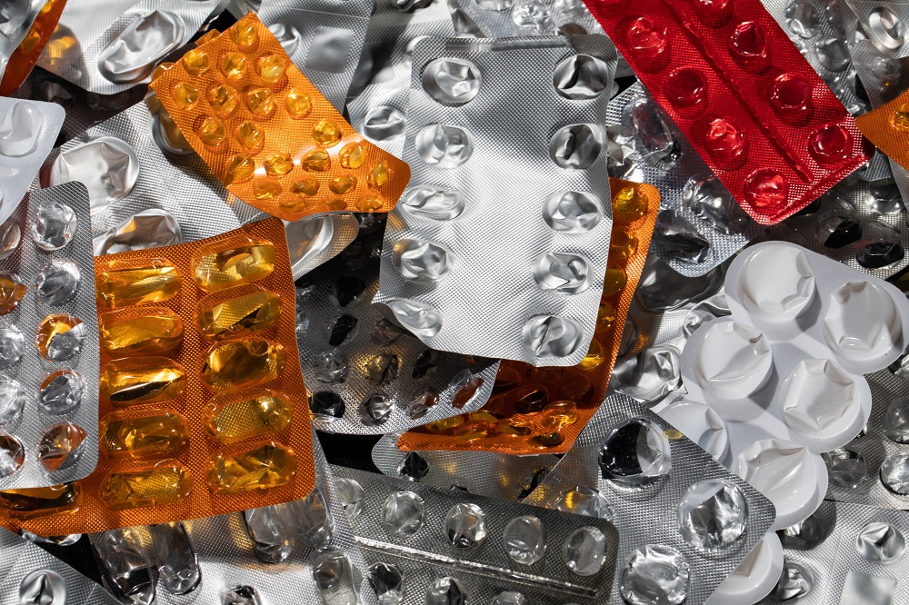 Na imagem, vê-se diversas embalagens vazias de medicamentos nas cores laranja, prata e vermelho.